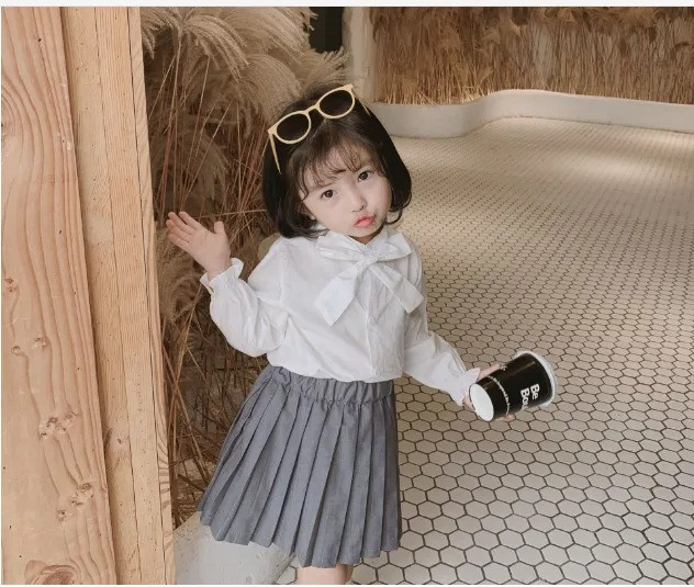 Bé gái mặc áo sơ mi trắng và quần jean